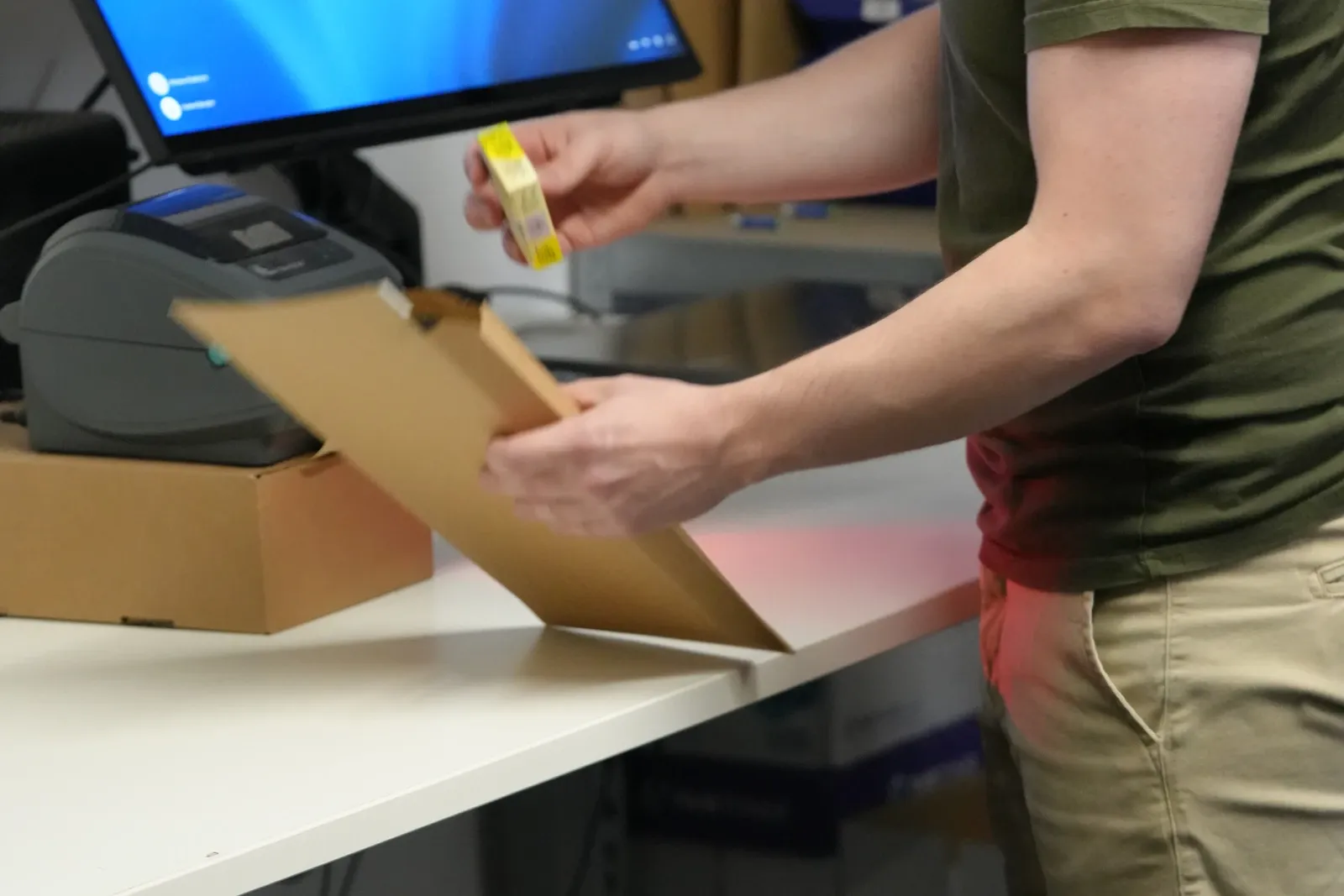 Hände beim Einpacken von Ware in einen Versandkarton